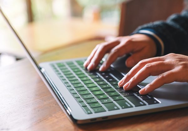 Close up of hands typing on a laptop keyboard