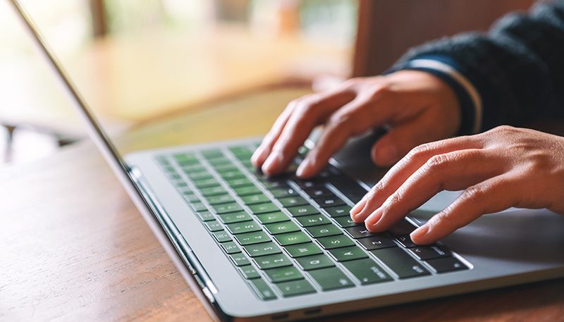 Close up of hands typing on a laptop keyboard