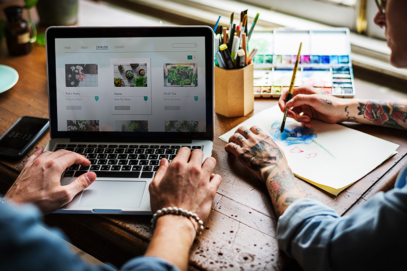 hands-searching-for-plants-buy-online-shop-2023-11-27-05-29-17-utc Two people working on a laptop building a website