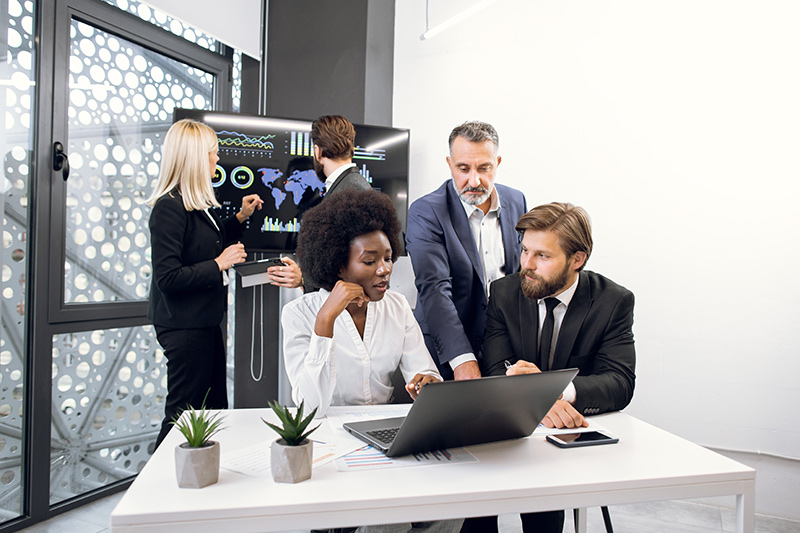 Group of people standing around a computer in an office