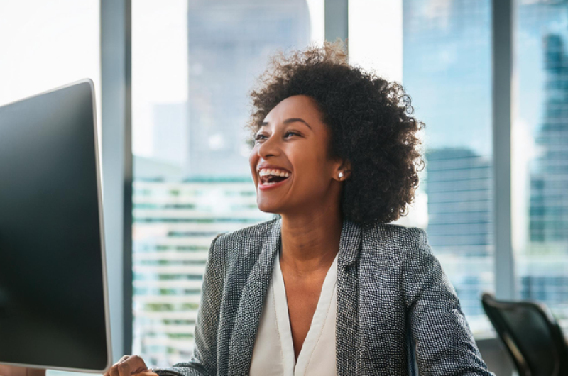 Woman laughing at computer desk