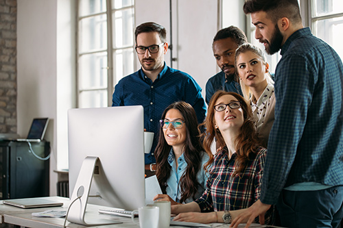 A group of people standing around a computer