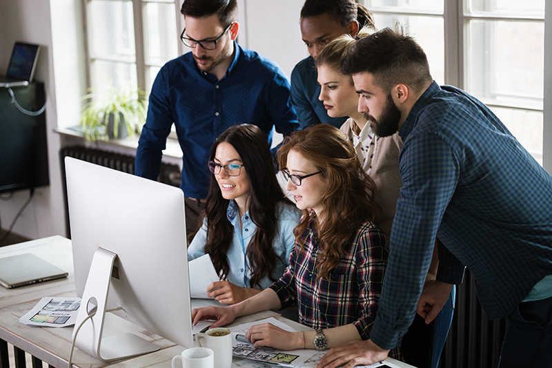 Group of web developers standing around a computer